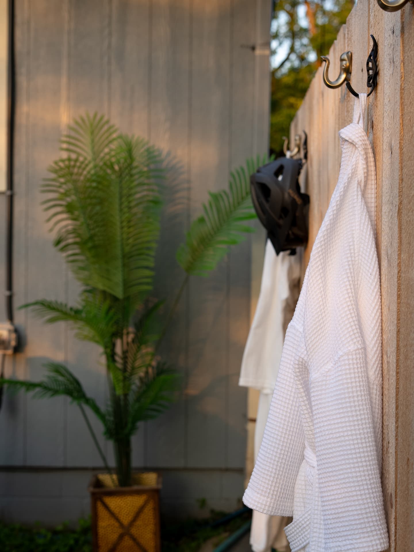 Waffle-knit robe hanging on a cedar fence by a palm
