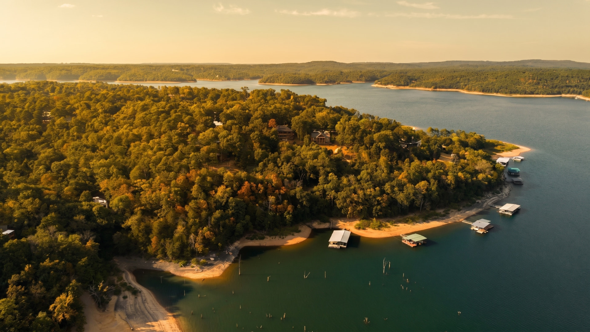 Aerial panorama of Beaver Lake shoreline, docks, and forested ridges at golden hour